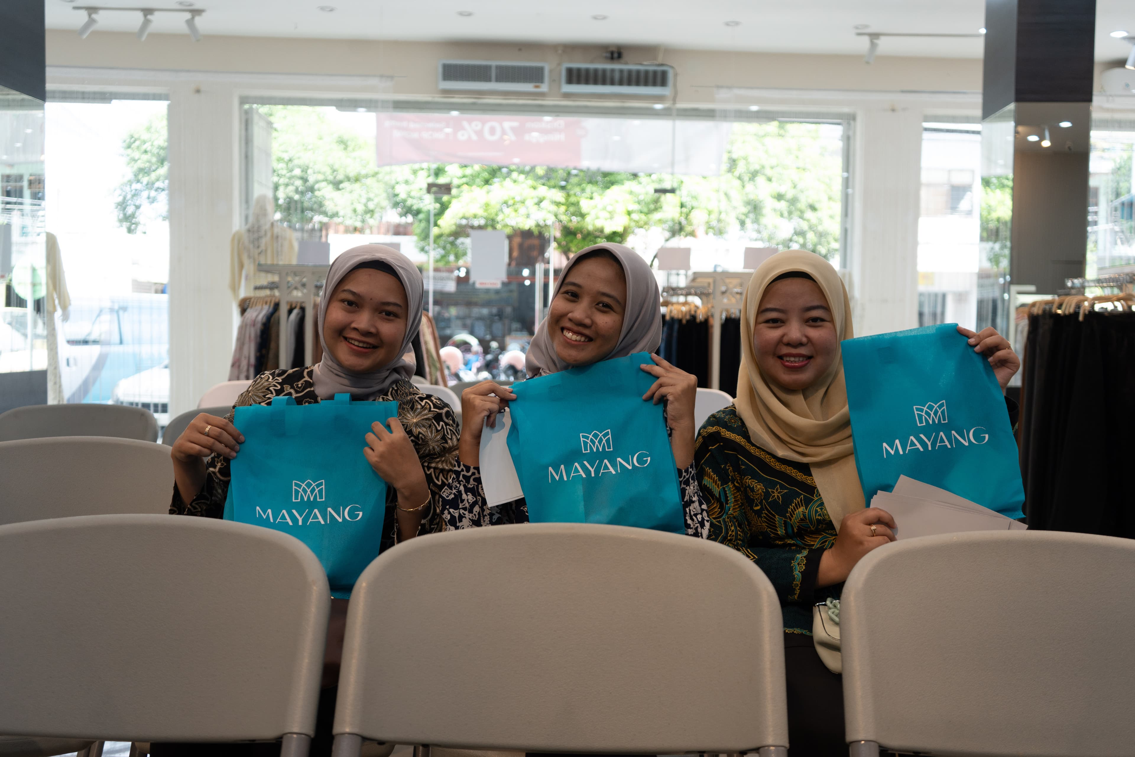 Peserta tersenyum memegang tas Mayang Collection